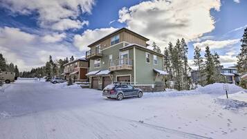 A multi-story residential building with a garage, surrounded by snow-covered ground and trees.