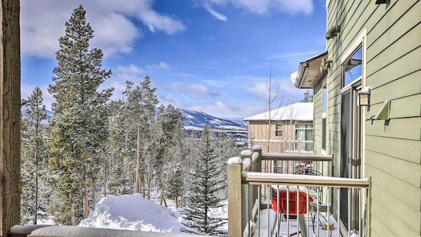A balcony with a view of snow-covered trees and a mountain in the background.