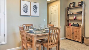 A dining area with a wooden table set for four, flanked by two framed pinecone artworks.