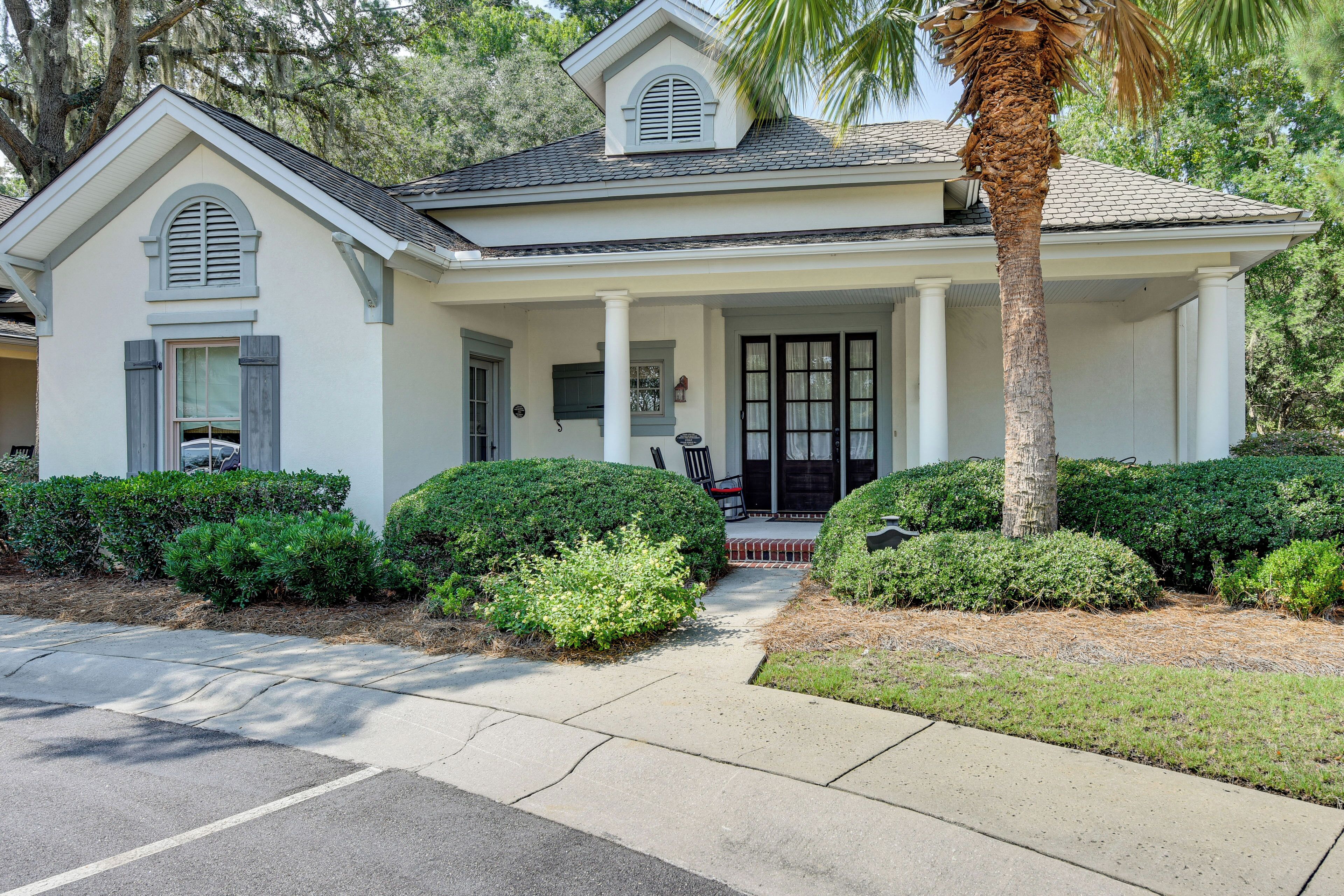 A two-story house with a front porch, a palm tree, and well-maintained landscaping.