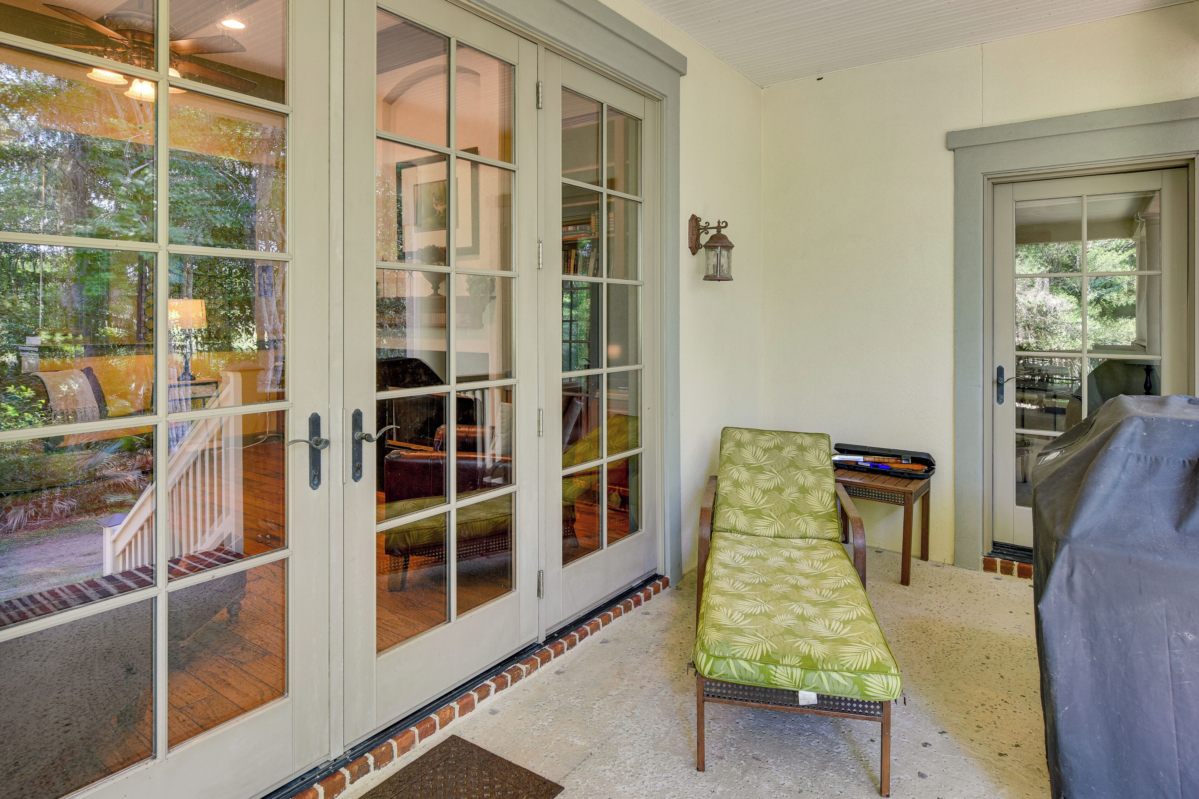A room with a sliding glass door, a bench, a small table, and a wall-mounted light fixture.