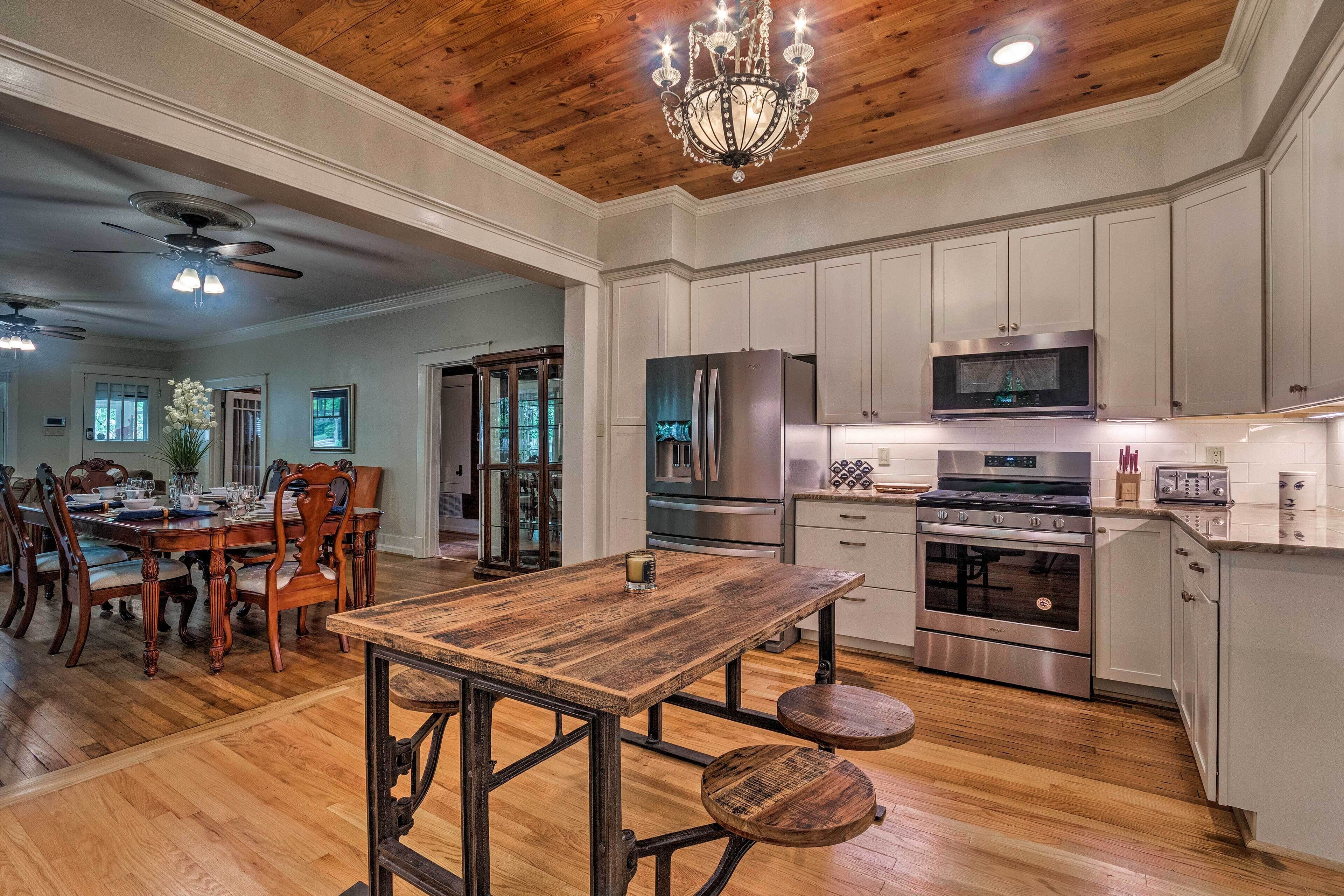 Una cocina amplia con suelo de madera, un comedor con una gran mesa de madera y electrodomésticos modernos.