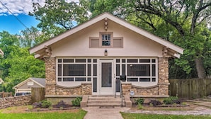 A two-story house with a stone facade, a front porch, and a garage. - Spacious & Updated 1920's Hsnp Craftsmen Home (Hot Springs)