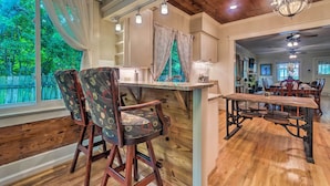 A dining area with a wooden table and chairs, a chandelier, and a view of the outdoors. - Spacious & Updated 1920's Hsnp Craftsmen Home (Hot Springs)