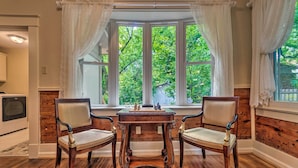 A room with a bay window, two wooden chairs, a small wooden table, and a television on the left. - Spacious & Updated 1920's Hsnp Craftsmen Home (Hot Springs)