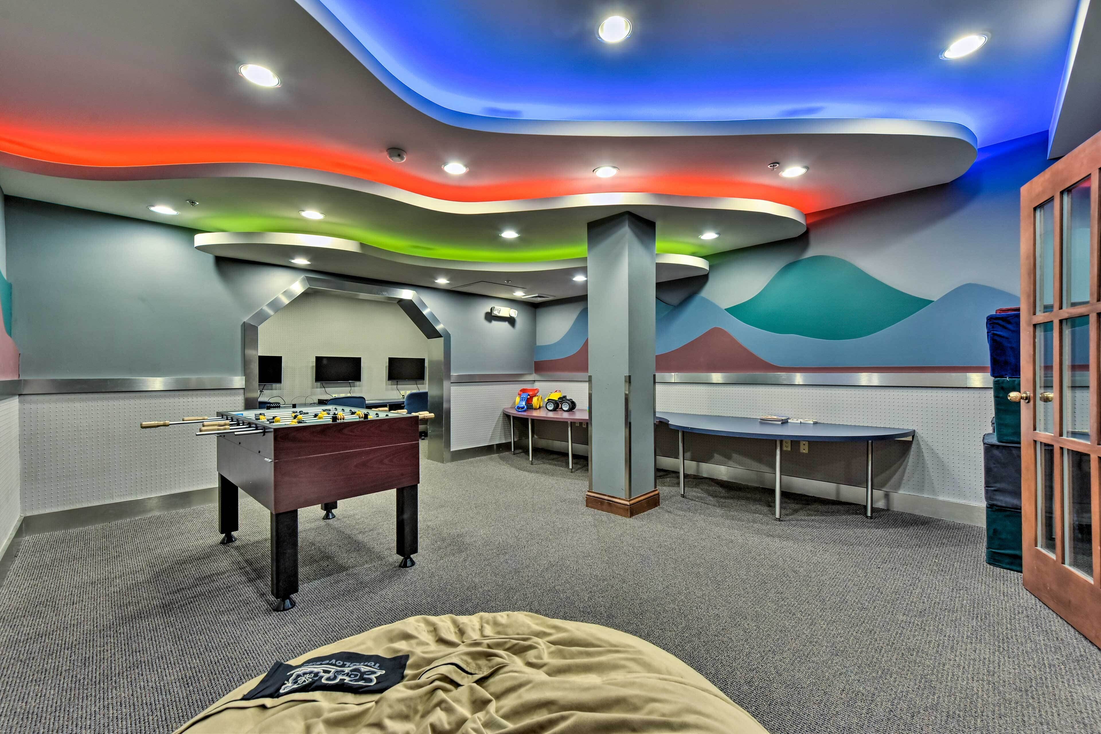 A room with a foosball table, a desk, and a sofa.