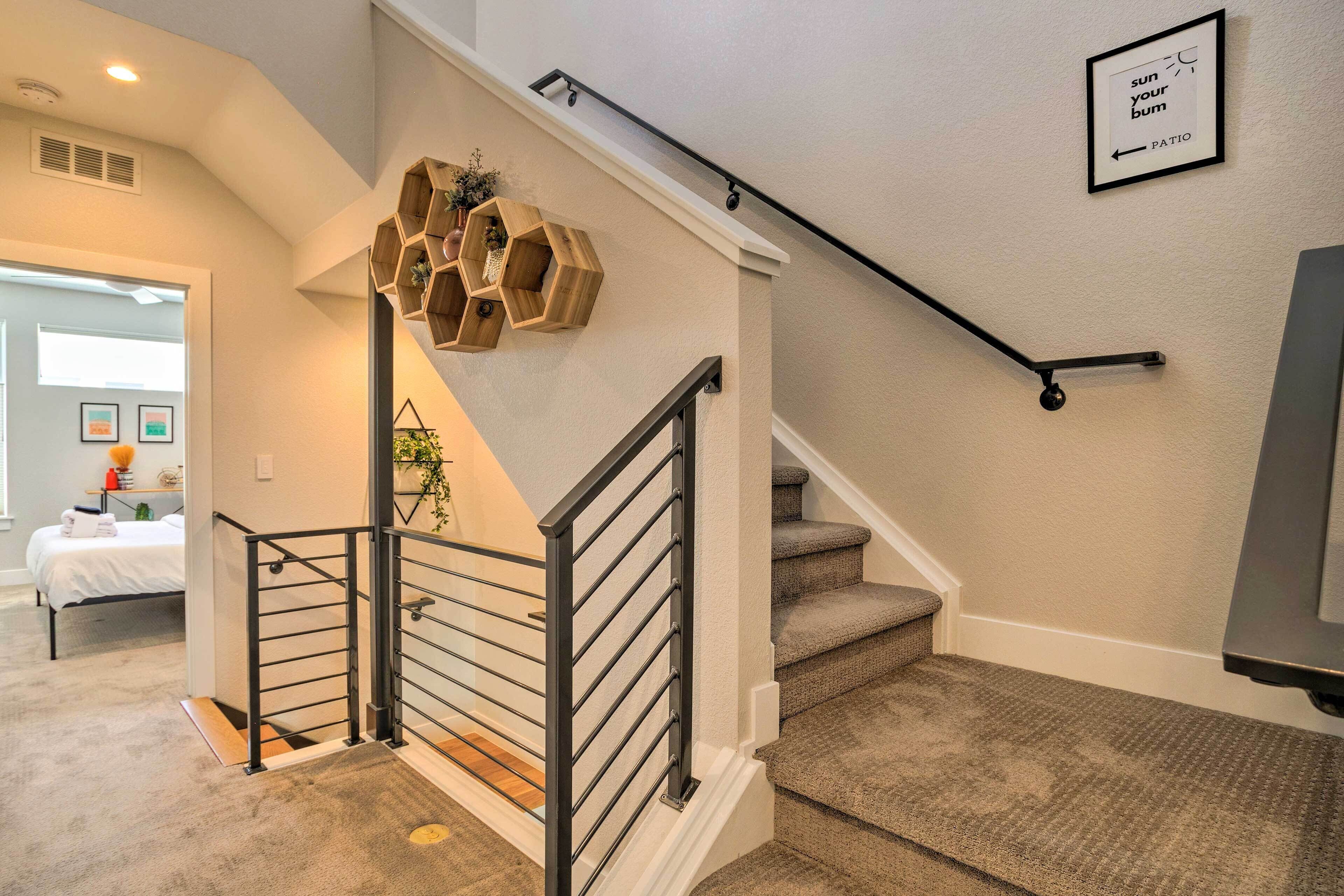 A staircase with a handrail, carpeted steps, and a wall-mounted hexagonal shelf with plants.