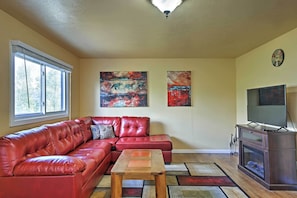 A living room with a red leather sofa, a wooden coffee table, a fireplace, and a television on a wooden stand. - Lake- & Mtn-view: Resort Hub in Silverthorne! (Silverthorne)