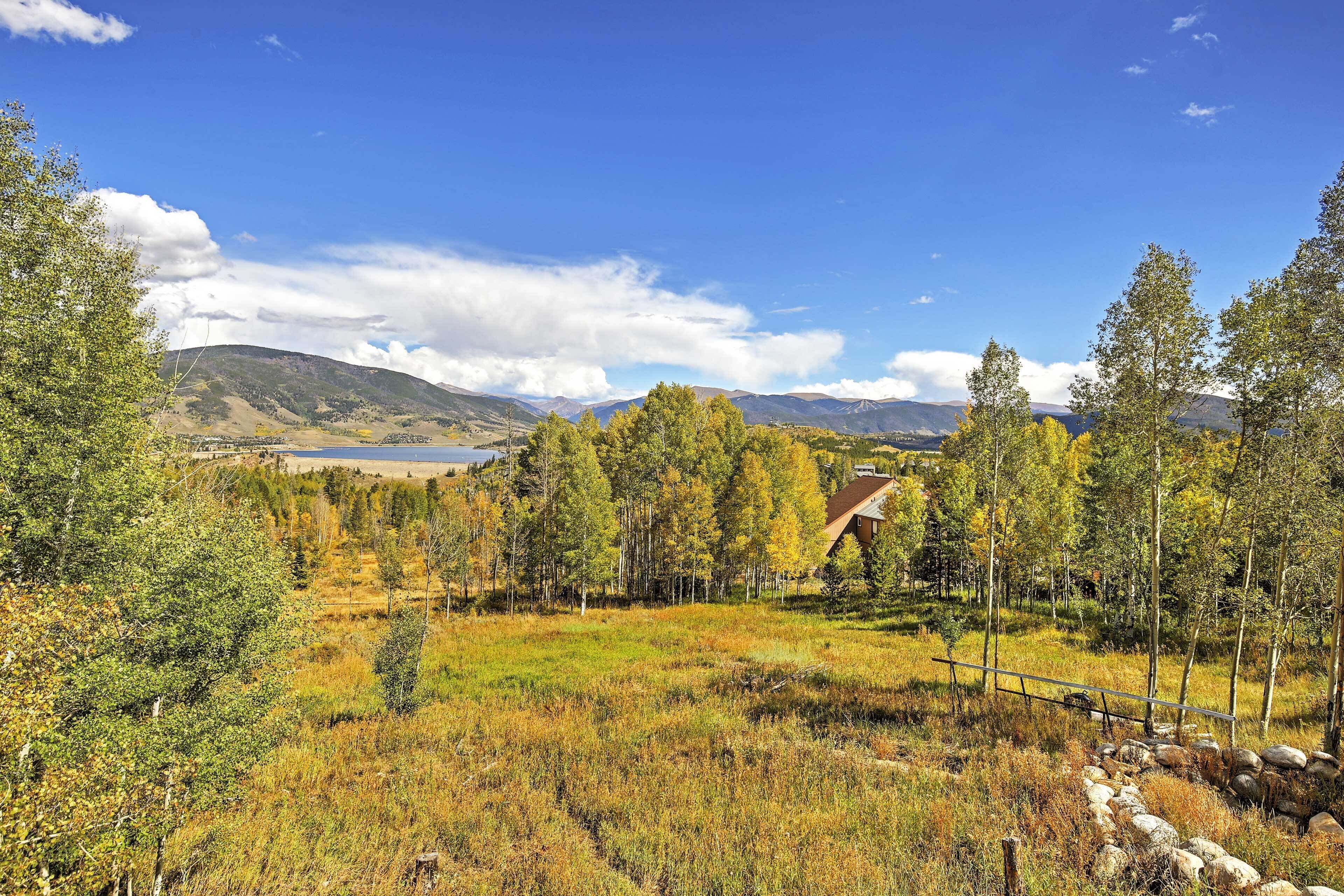 Un paysage rural avec une maison entourée d’arbres et un ciel dégagé.
