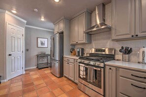 A kitchen with white cabinets, a stainless steel refrigerator, a gas stove, and a tiled backsplash.