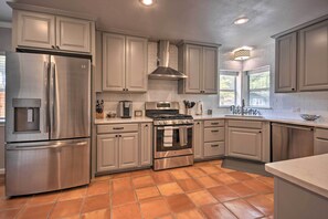 A modern kitchen with stainless steel appliances, white cabinetry, and a tiled floor.