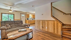 Un salón espacioso con suelo de madera, un sofá, una mesa de centro y un ventilador de techo.