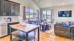 A spacious living area with a dining table, a sofa, and a TV mounted on the wall. - Alma Retreat w/ Mtn Views ~ 17 Mi to Breck! (Alma)