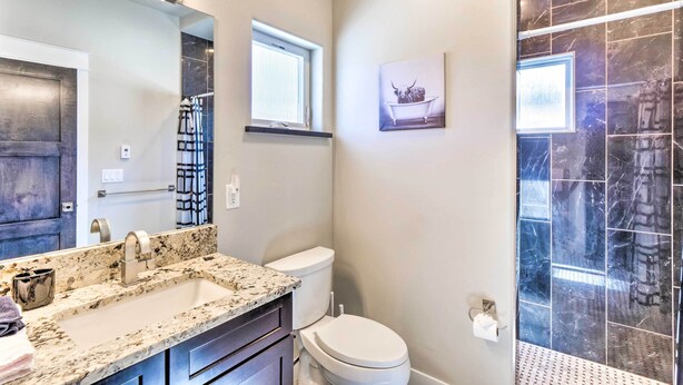 A bathroom with a marble sink, a toilet, and a shower with dark tiles. - Alma Retreat w/ Mtn Views ~ 17 Mi to Breck! (Alma)