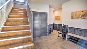 A staircase leading to a dark wooden door, a bench, and a wall-mounted artwork in a modern interior. - Alma Retreat w/ Mtn Views ~ 17 Mi to Breck! (Alma)