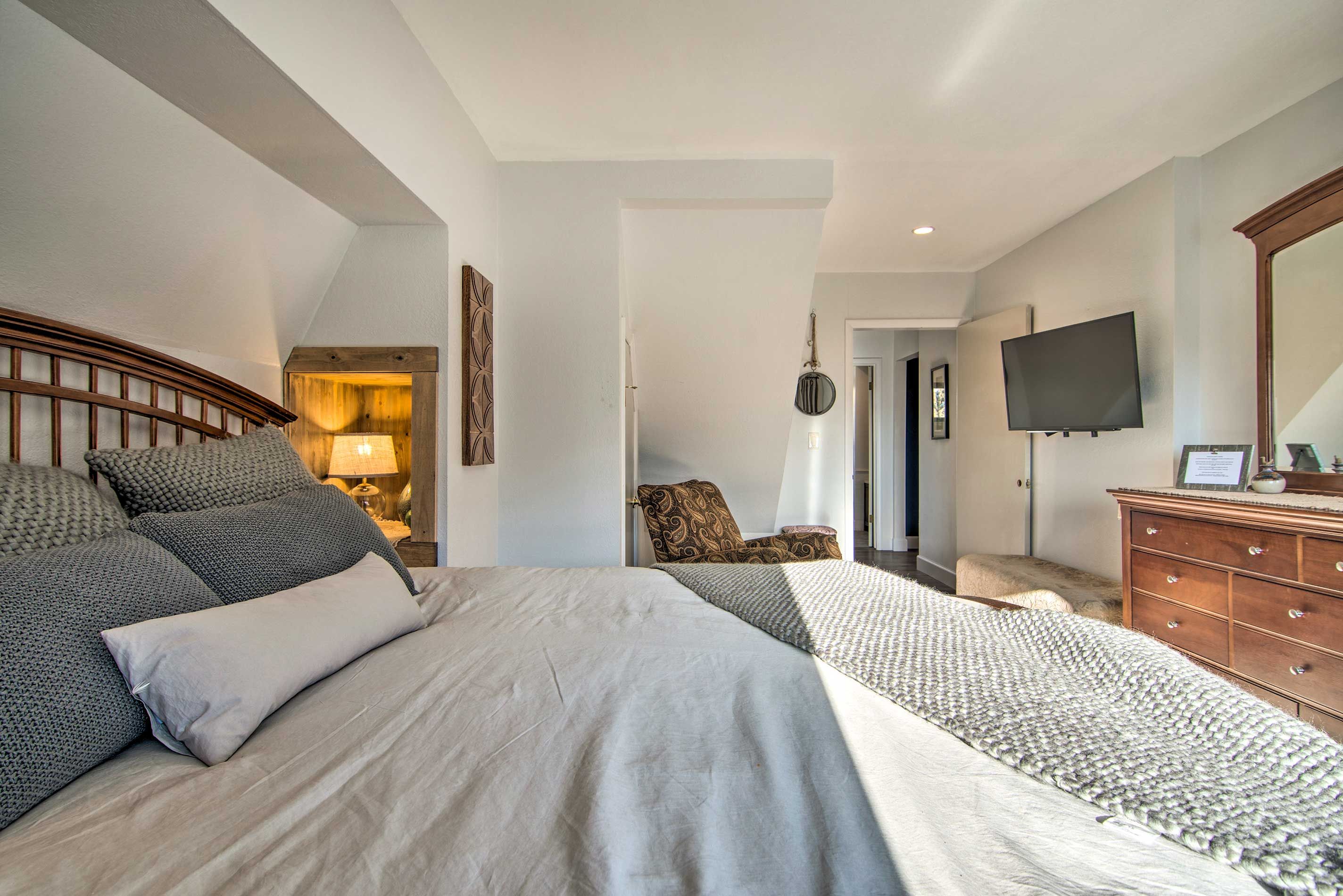 A bedroom with two beds, a dresser, a TV, and a lamp.