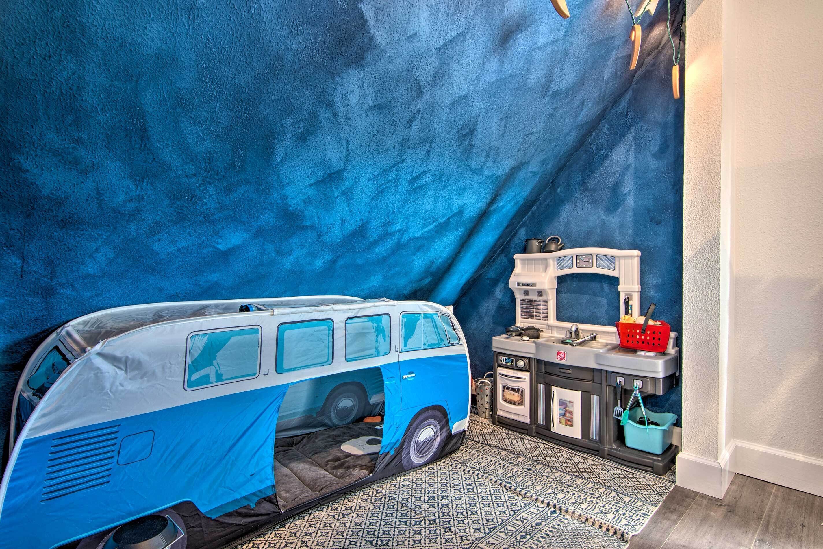 A room with a van-shaped bed, a kitchenette, and a patterned floor.
