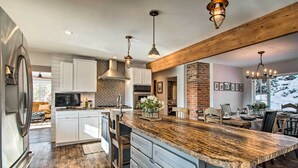 A modern kitchen with a large island, white cabinetry, and a wooden ceiling. - Outdoor Kitchen & Swim Spa: 1-acre Grand Lake Home (Grand Lake)