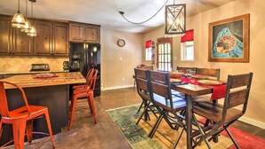 A kitchen with wooden cabinets, a central island, red chairs, and a dining table with a red tablecloth.