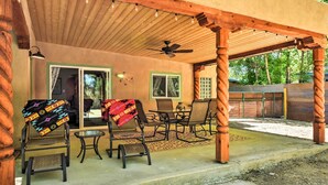 An outdoor patio with wooden furniture, a ceiling fan, and string lights.