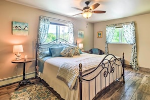 A bedroom with a bed, two bedside tables, a ceiling fan, and a window with curtains.