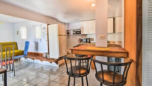 A compact kitchen with white cabinets, a microwave, and a wooden island with bar stools. - Tropical Oasis: Bay Views ~ 2 Mi to Playa Sardinas (Culebra)