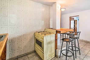 Una cucina con piano cottura a gas, lavello e tavolo in legno con sgabelli da bar.