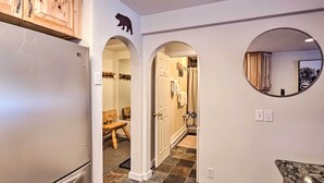 A modern kitchen with a refrigerator, wooden cabinets, and a stone tile floor. - Ski-in/ski-out Condo w/ Hot Tub on Copper Mountain (Copper Mountain)