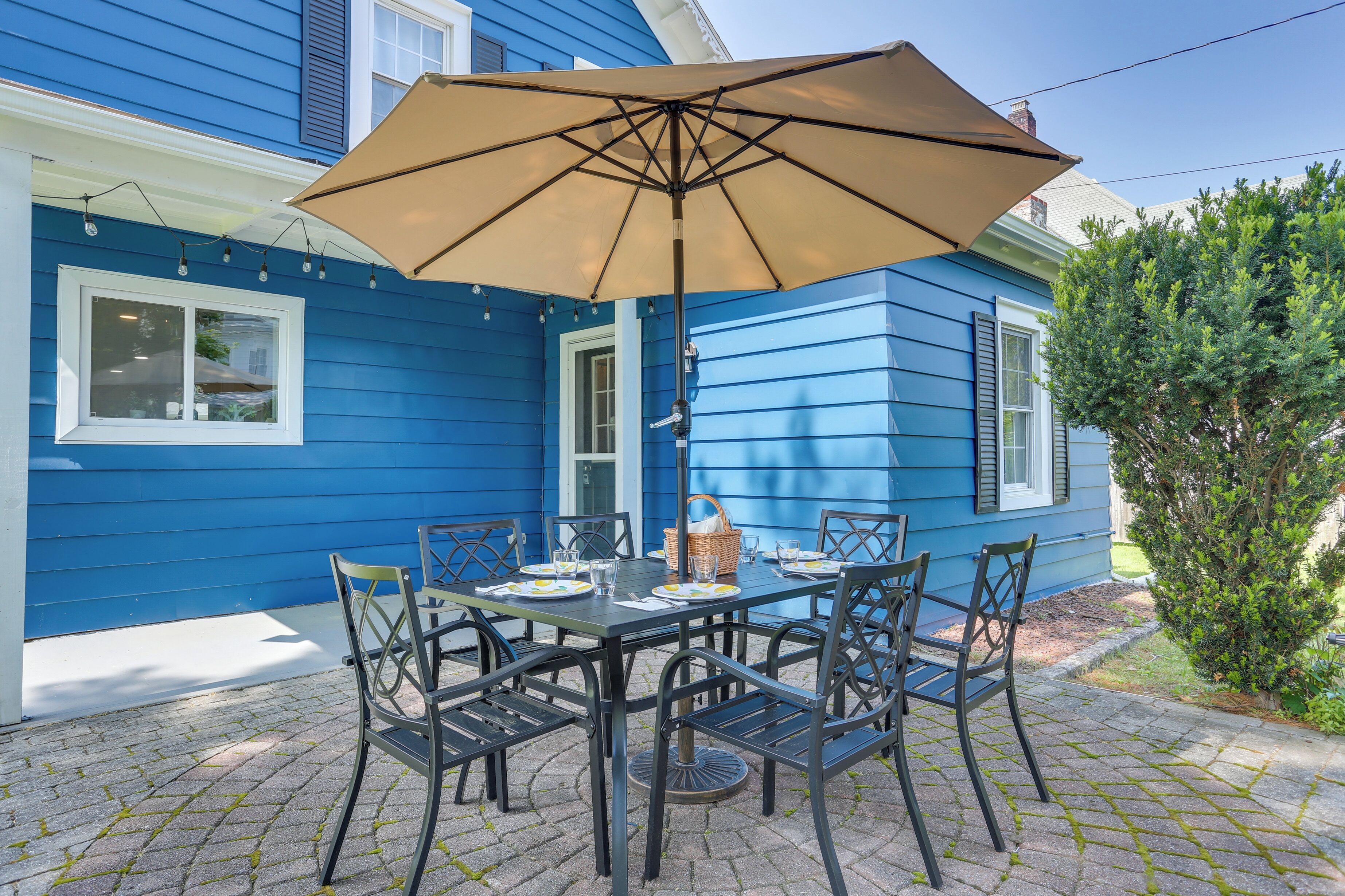 A patio with a table set for four, surrounded by chairs, under a large umbrella.