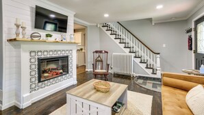 A living room with a fireplace, a television mounted above it, a staircase leading to another level, and a cozy seating area with a sofa. - Bright Cornwall-on-hudson Vacation Rental! (Cornwall)
