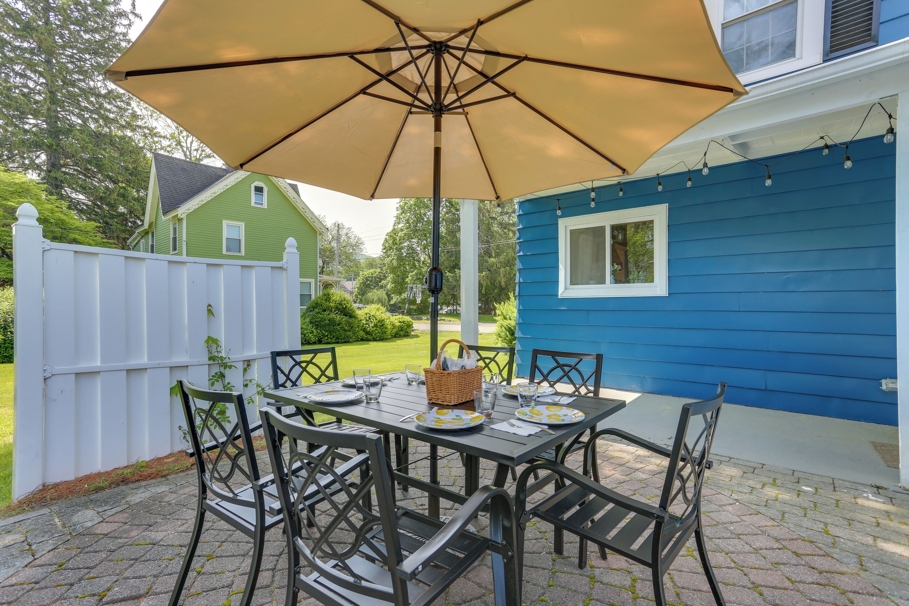 A patio with a table set for four, surrounded by chairs, under a large umbrella.