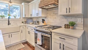 A modern kitchen with white cabinets, a stainless steel stove, and a brick backsplash. - Bright Cornwall-on-hudson Vacation Rental! (Cornwall)