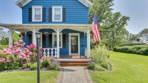 A blue house with a porch, an American flag, and a brick pathway leading to the entrance. - Bright Cornwall-on-hudson Vacation Rental! (Cornwall)