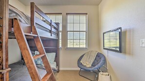 A room with a bunk bed, a chair, a television, and a window with blinds. - Ski, Hike & Golf: Granby Condo w/ Shared Amenities (Granby)