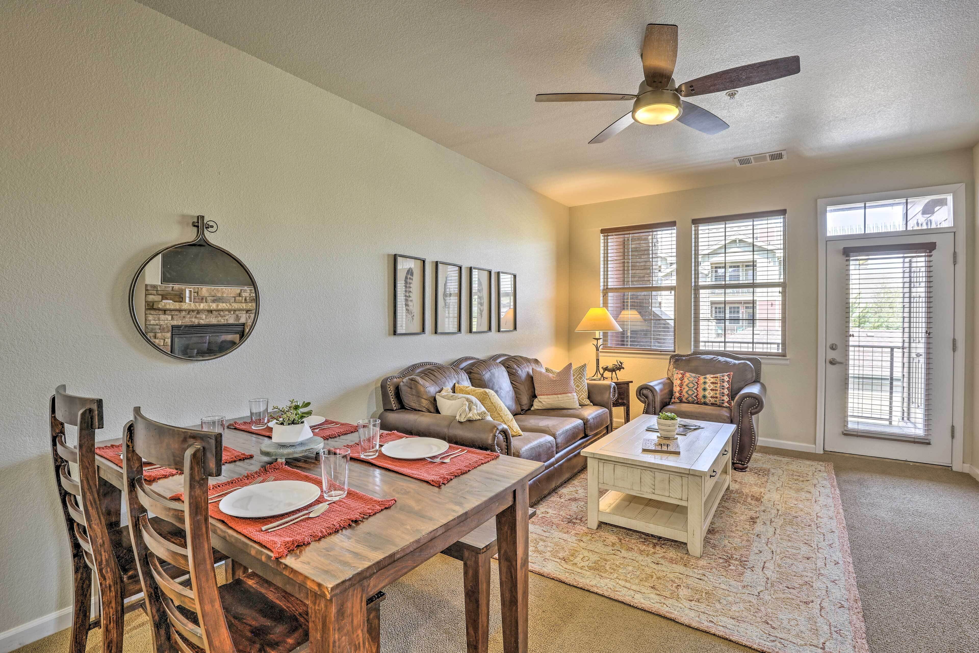 A living room with a dining table set for four, a sofa, a coffee table, and a ceiling fan.