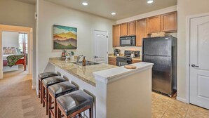 A kitchen with wooden cabinets, a stainless steel refrigerator, a microwave, and a granite countertop. - Ski, Hike & Golf: Granby Condo w/ Shared Amenities (Granby)