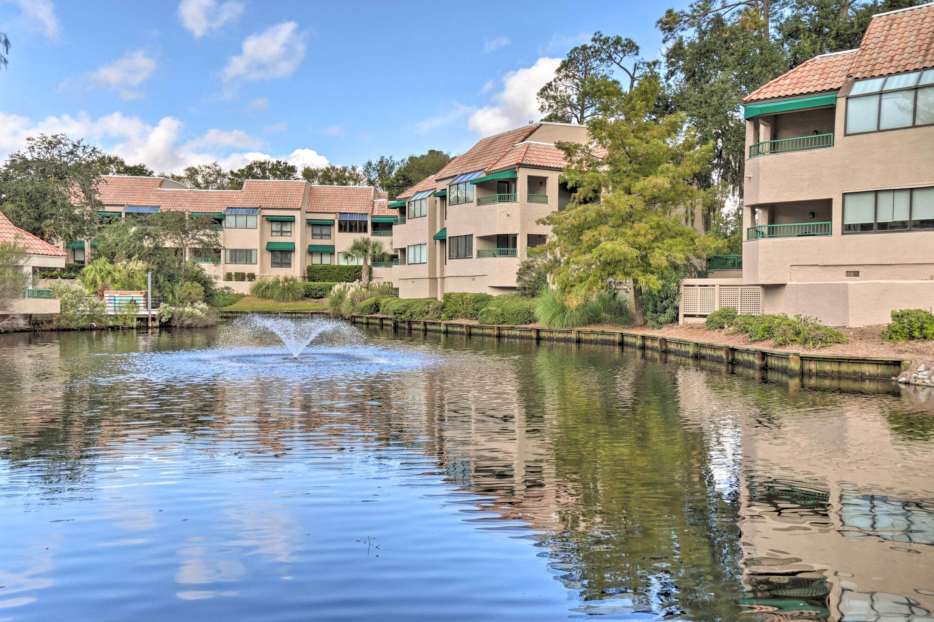 A tranquil courtyard with a fountain, surrounded by multi-story buildings with balconies and large windows.