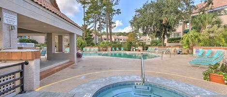 A hotel pool area with a hot tub, lounge chairs, and a sign warning about children under 1 not being permitted in the hot tub.