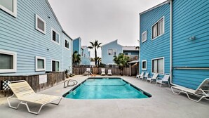 A swimming pool area with lounge chairs and a wooden fence. - Corpus Christi Condo w/ Pool Access, Walk to Beach (Corpus Christi)