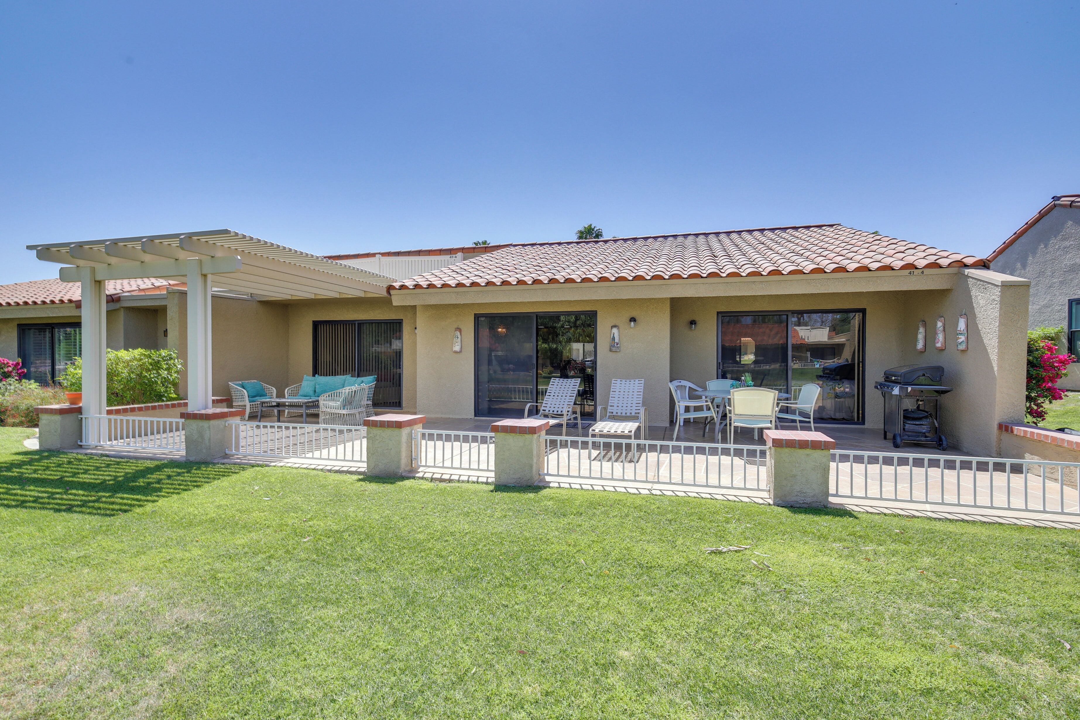 A two-story house with a patio area featuring outdoor furniture and a grill.
