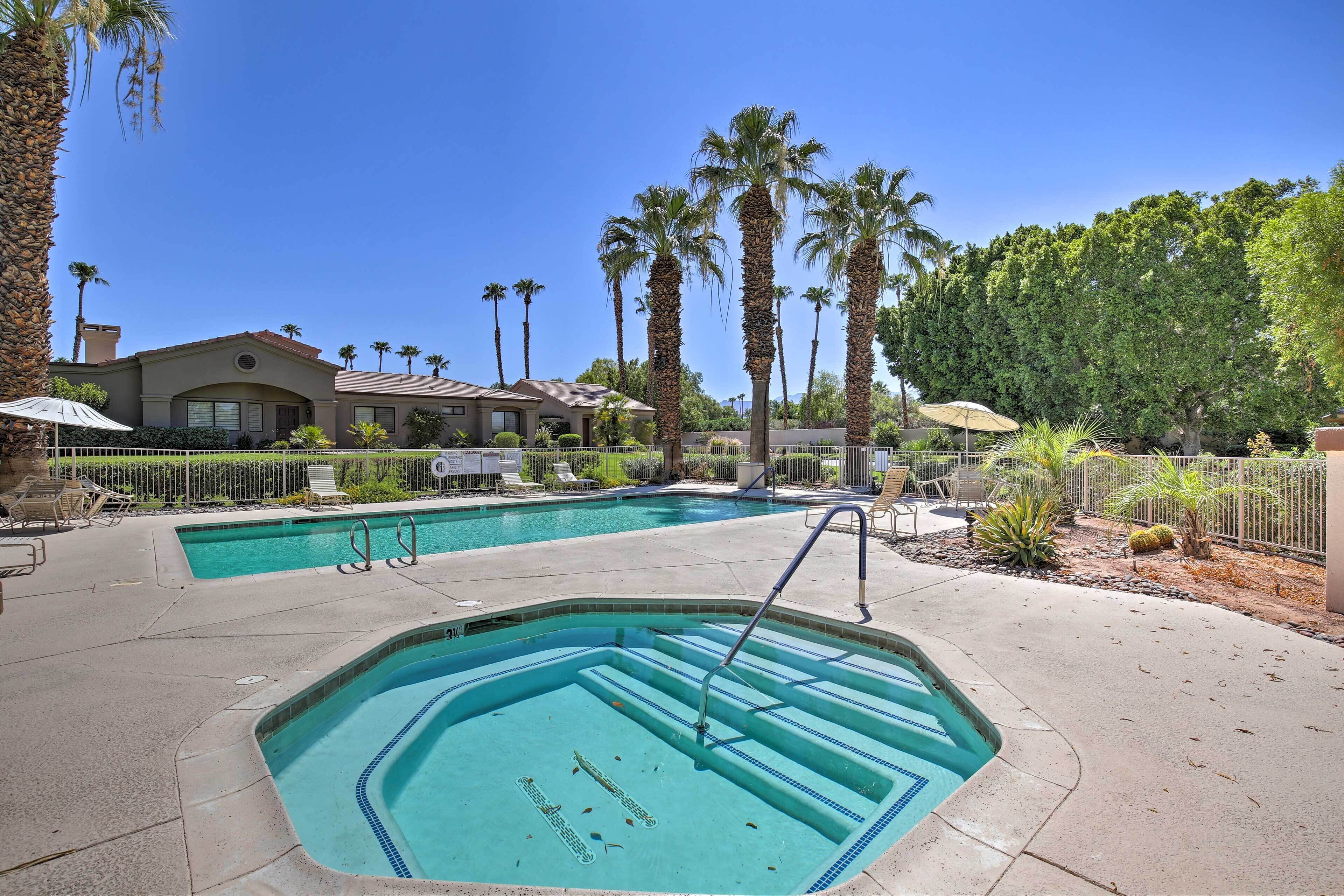 A swimming pool with steps, surrounded by palm trees and a fence.