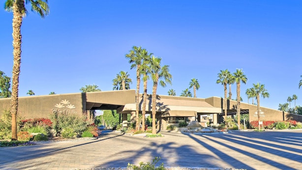 A hotel entrance with palm trees, a clear blue sky, and a paved driveway. - Beautiful Gated Country Club, Prime Location (Palm Desert)