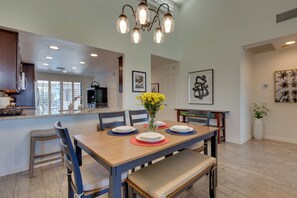 Un coin repas avec une table en bois dressée pour quatre personnes, des chaises et un vase rempli de fleurs jaunes.