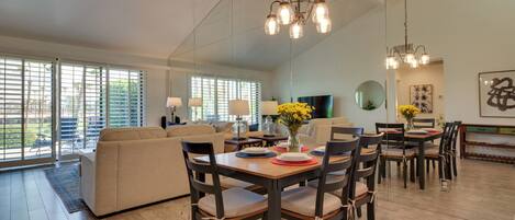 A spacious living area with a dining table set for four, a sofa, and a television.