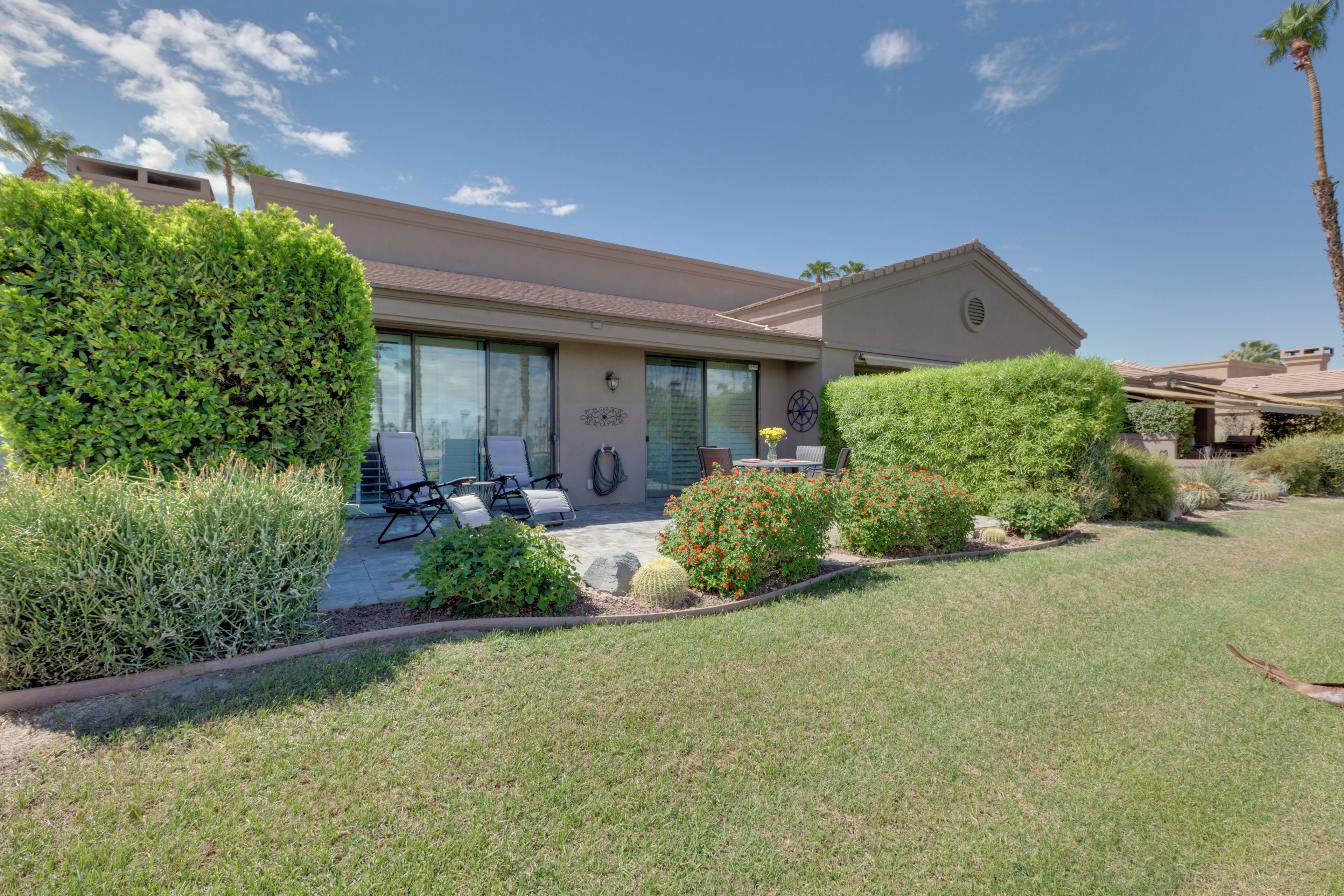 A residential house with a patio, outdoor seating, and well-maintained landscaping.