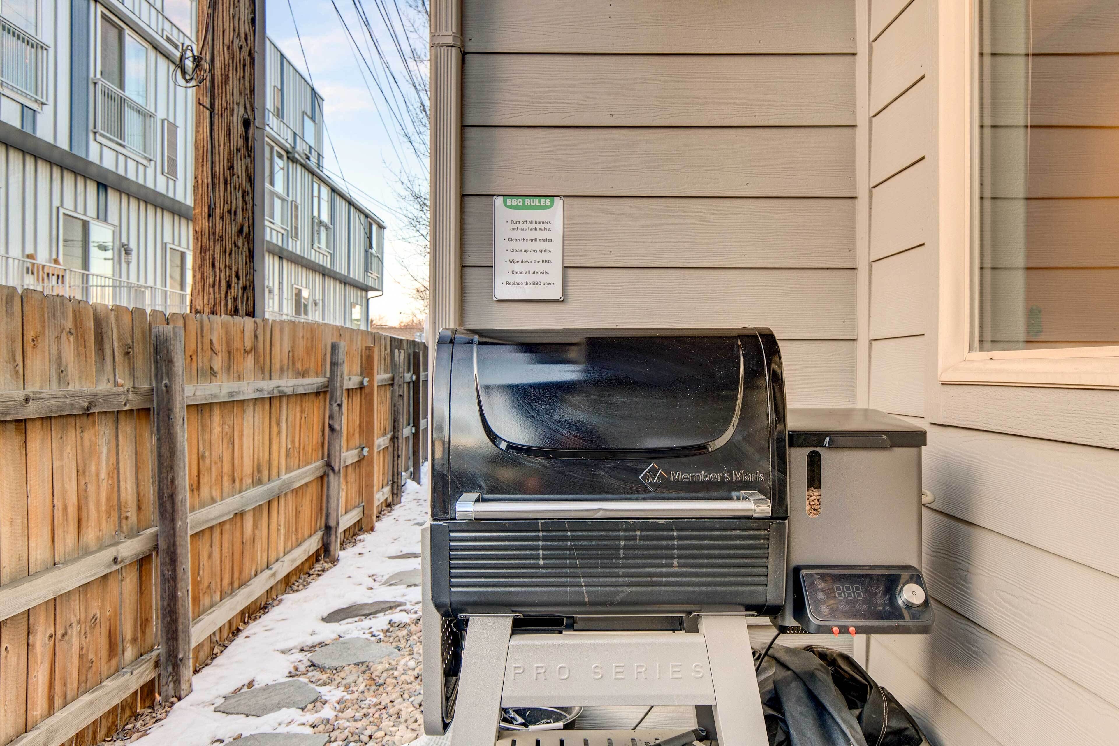 A Weber's Master Pro Series grill attached to a house exterior with a wooden fence and a sign listing BBQ rules.