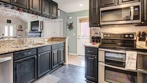 A modern kitchen with dark cabinetry, stainless steel appliances, and a granite countertop. - Denver Townhome in Highlands w/ Spacious Yard! (Denver)
