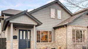 A two-story house with a dark front door, a large window, and a brick exterior. - Denver Townhome in Highlands w/ Spacious Yard! (Denver)