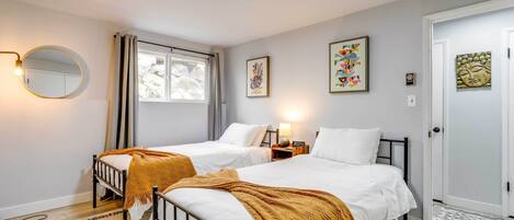 Quarto com duas camas, um espelho redondo e obras de arte nas paredes.