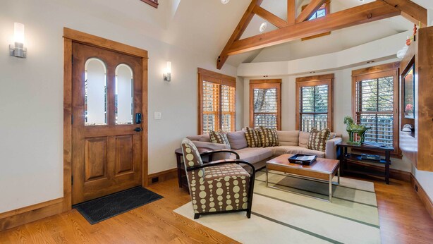 A spacious living room with wooden beams, a sofa, a patterned armchair, and a coffee table. - Downtown Breckenridge Cottage: Walk to Main St! (Breckenridge)
